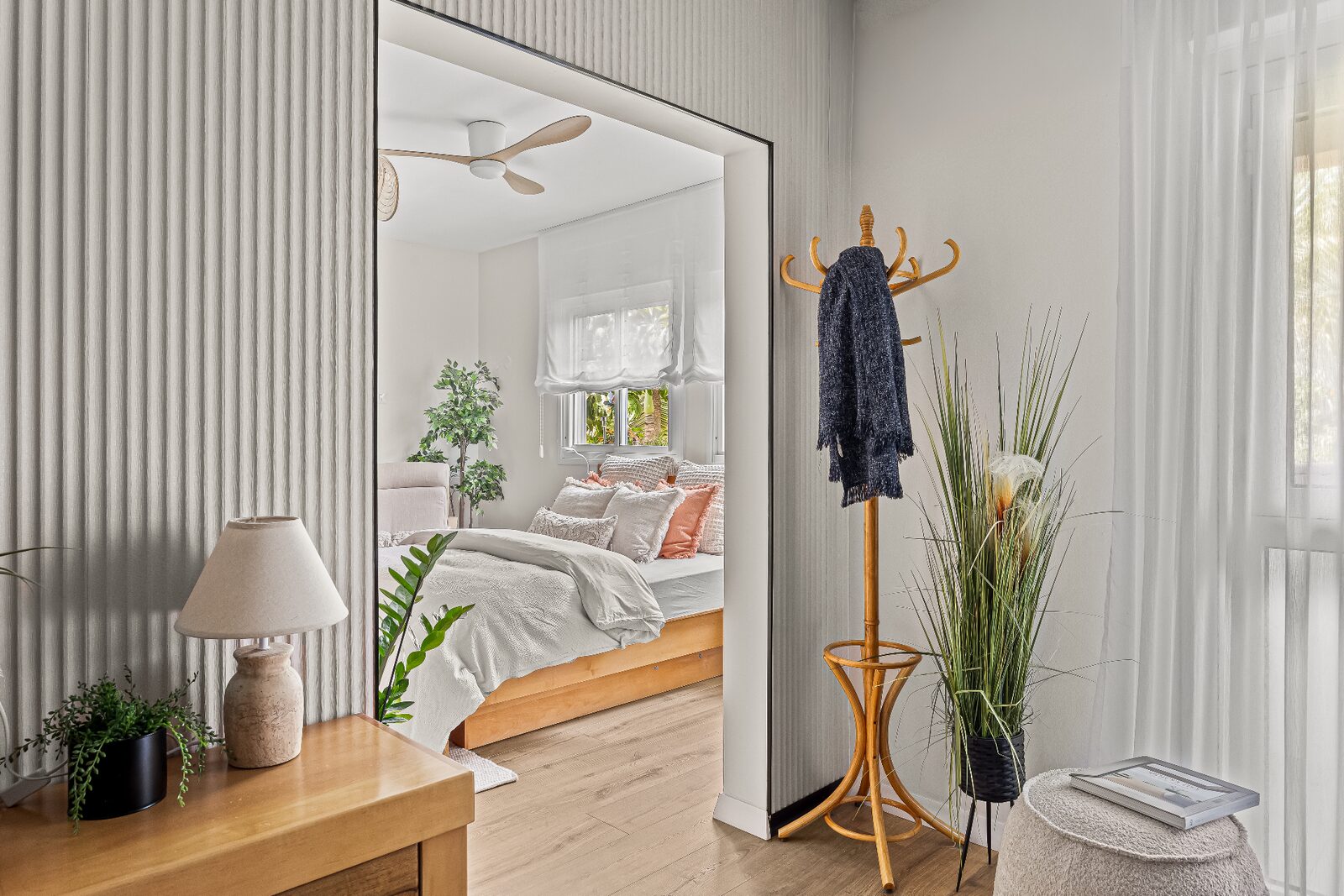 Rishon LeZion bedroom view through ribbed portal toward bed and soft Roman shade
