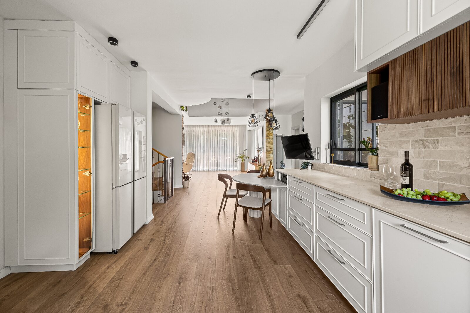 Rishon LeZion open-plan kitchen and dining with wood flooring, fluted feature cabinetry and stone backsplash