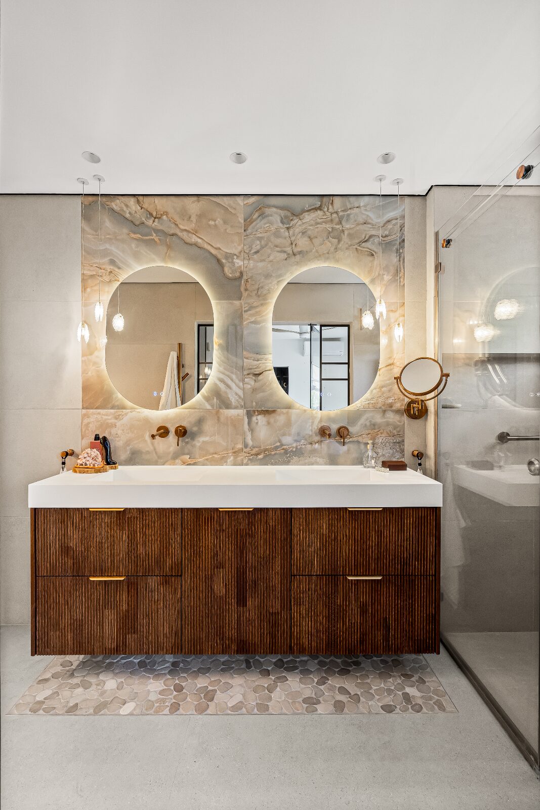 Rishon LeZion master bathroom with twin backlit oval mirrors and fluted wood double vanity