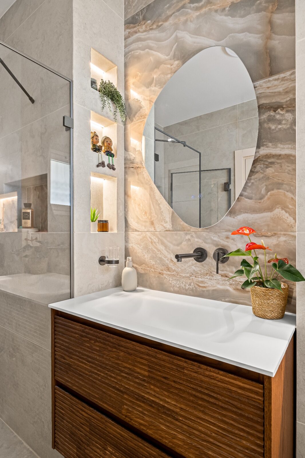 Rishon LeZion guest bathroom detail with organic mirror and backlit onyx niches