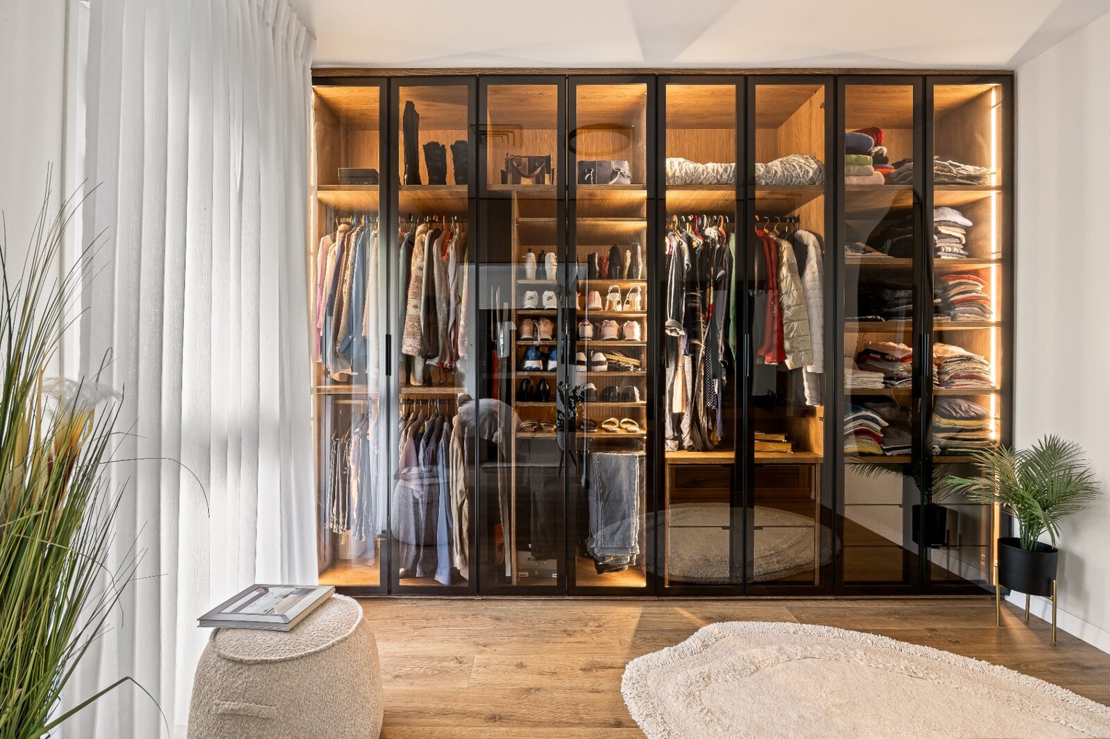 Rishon LeZion walk-in closet wide view with glass wardrobes and integrated lighting