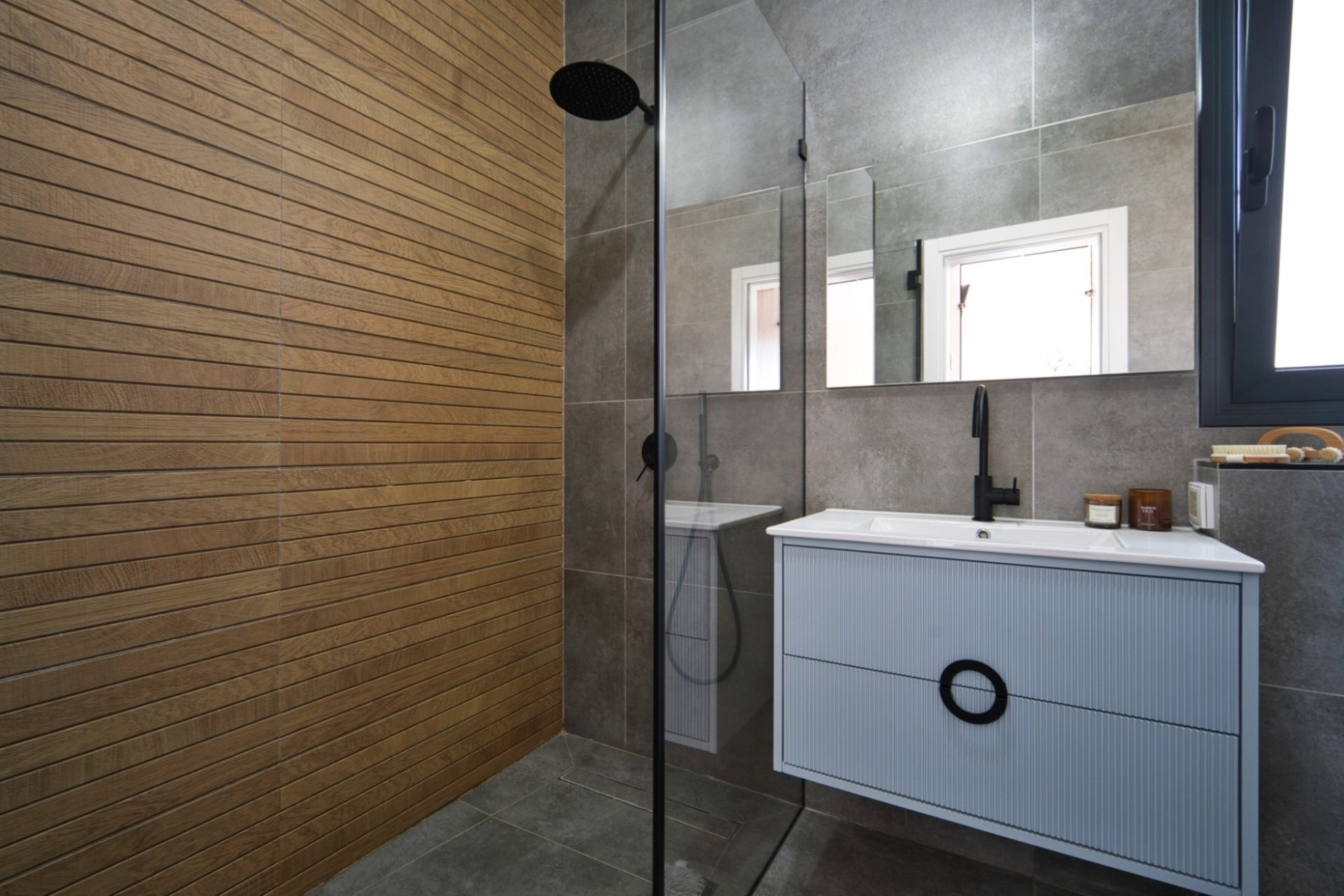 Rishon LeZion bathroom with wood slat wall and walk-in shower